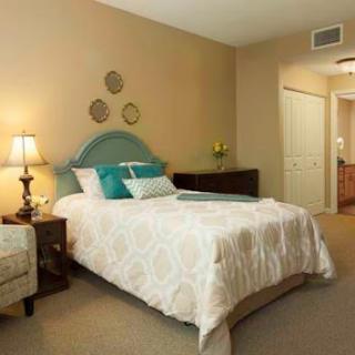 A cozy bedroom featuring a neatly made bed, a decorative lamp, and tasteful wall decor.