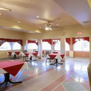An empty restaurant dining area with red tablecloths and ample natural light.