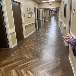 A long, well-lit hallway with wooden flooring and multiple doors on either side.