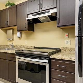 A modern kitchen with dark cabinets, stainless steel appliances, and granite countertops.