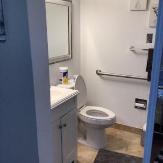 A small bathroom with a toilet, sink, mirror, and towel rack.