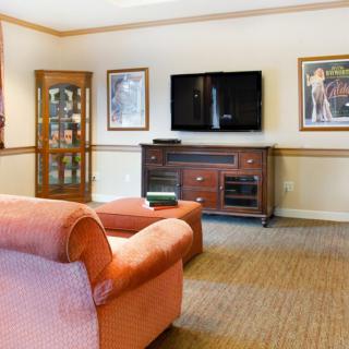A cozy living room with a flat-screen TV, comfortable sofa, and decorative artwork.