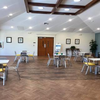 A spacious and bright cafe interior with neatly arranged tables and chairs on a wooden floor.