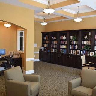 A cozy library space featuring bookshelves, a seating area, and a computer desk.