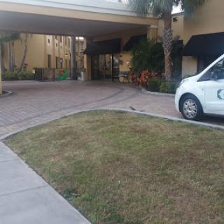 A view of the entrance to a hotel, featuring a neatly maintained parking area and a white vehicle.