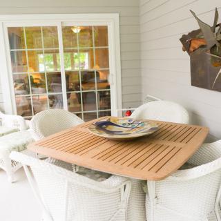 Cozy outdoor patio with a wooden table and white chairs, perfect for relaxation.
