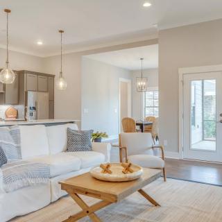 A modern open-concept living space with a cozy living room and a kitchen area, showcasing neutral colors and ample natural light.