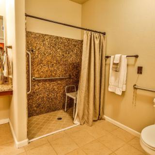 An accessible bathroom with a walk-in shower, grab bars, and a towel rack.