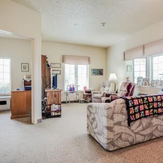 A cozy living room featuring a patterned sofa, large windows, and warm decor.
