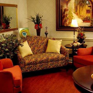A cozy living room with a patterned sofa, two orange armchairs, and a warmly lit table lamp.