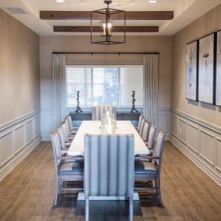 A modern dining room with elegant decor and a long table surrounded by chairs.
