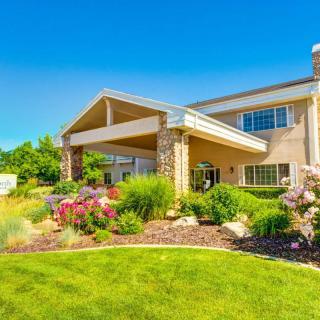 A beautifully landscaped building with a vibrant garden and lush green lawn under a clear blue sky.