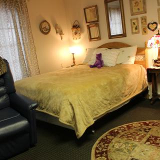 A cozy bedroom with a neatly made bed, decorative wall art, and warm lighting.