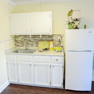 A compact kitchen with white cabinets and a refrigerator.