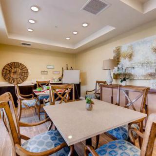 A cozy dining room with a central table and chairs, adorned with decorative elements and artwork.