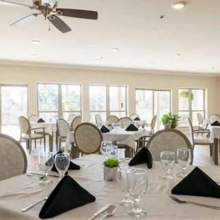 A beautifully arranged dining area featuring elegant tables set for a meal with napkins and glassware, bathed in natural light.