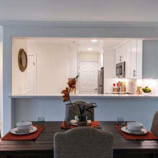 A modern kitchen with an open layout dining area, featuring a minimalist table setting and contemporary design.