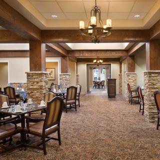 An elegant dining area with neatly arranged tables and chairs, adorned by a central chandelier.