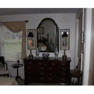 A well-decorated bedroom features a dresser with a mirror and lamps.