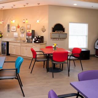 A cozy cafe interior with colorful chairs and tables, featuring modern decor and a vending machine.