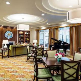 A beautifully decorated lounge room featuring a grand piano, elegant lighting, and comfortable seating arrangements.