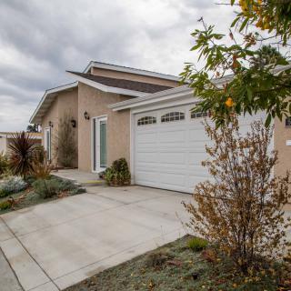 A suburban house with a garage and driveway, surrounded by landscaping under a cloudy sky.