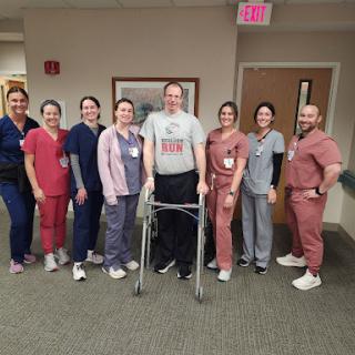 A group of healthcare professionals proudly supporting a patient in rehabilitation.