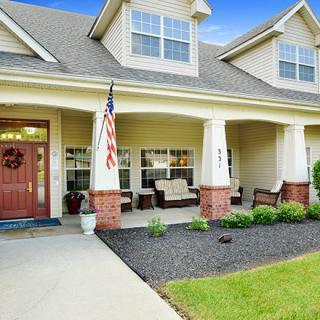 A welcoming house with a spacious porch and an American flag.