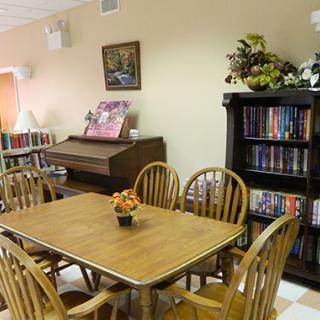 A cozy reading area with a table, chairs, bookshelf, and a piano.