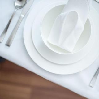 An elegant table setting featuring white plates, a folded napkin, and cutlery arranged neatly.