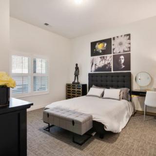 A modern bedroom featuring a stylish bed with decorative artwork on the wall and neutral color palette.
