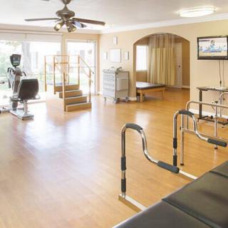 A well-equipped rehabilitation and physical therapy room with exercise equipment and parallel bars.