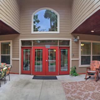 A welcoming entrance with red double doors and patio seating in a residential setting.