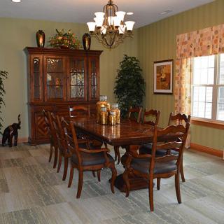 A well-furnished dining room with a large wooden table, chairs, and a chandelier overhead.
