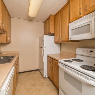 A compact kitchen featuring wooden cabinets and essential appliances.