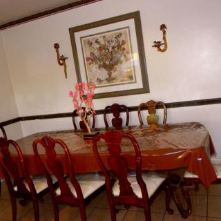 A well-decorated dining room featuring a polished wooden table, matching chairs, and floral wall art.