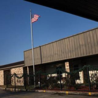 An exterior view of a building with an American flag on a pole.