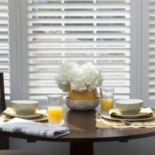 A cozy dining table set for breakfast with flowers and orange juice.