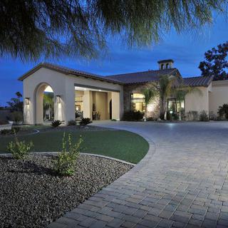 Modern residential house with a well-lit driveway during the evening.