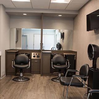 A modern hair salon with styling stations and chairs, featuring mirrors and a clean interior design.