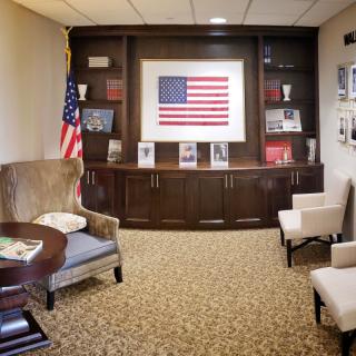 An office seating area with an American flag display, bookshelves, and chairs.
