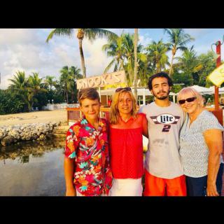 A family enjoying their time together at a tropical beach destination, surrounded by palm trees and sunlight.