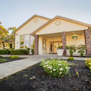 A well-maintained house with a landscaped front yard, featuring flower beds and a welcoming entrance.