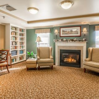 A cozy living room with armchairs, a fireplace, and built-in bookshelves.