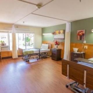 A bright and spacious hospital room with two patient beds and large windows.