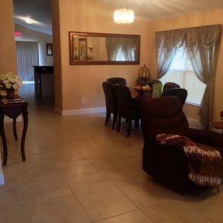 A cozy living and dining area featuring elegant furniture, a chandelier, and decorative curtains.