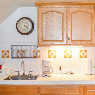 A cozy kitchen with wooden cabinets, a sink, and a clock on the wall.