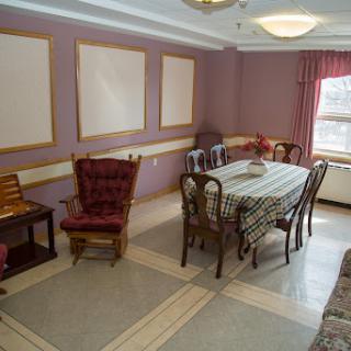 A cozy dining room featuring a patterned tablecloth, wooden chairs, and elegant decoration.