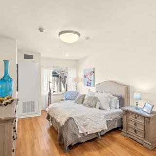A cozy bedroom with a neatly made bed, nightstands, and soft lighting.