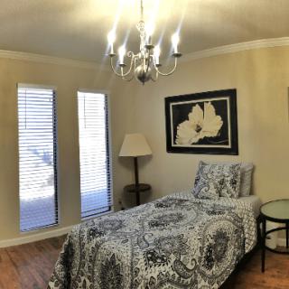 A cozy bedroom with a single bed, featuring elegant decor and a chandelier.